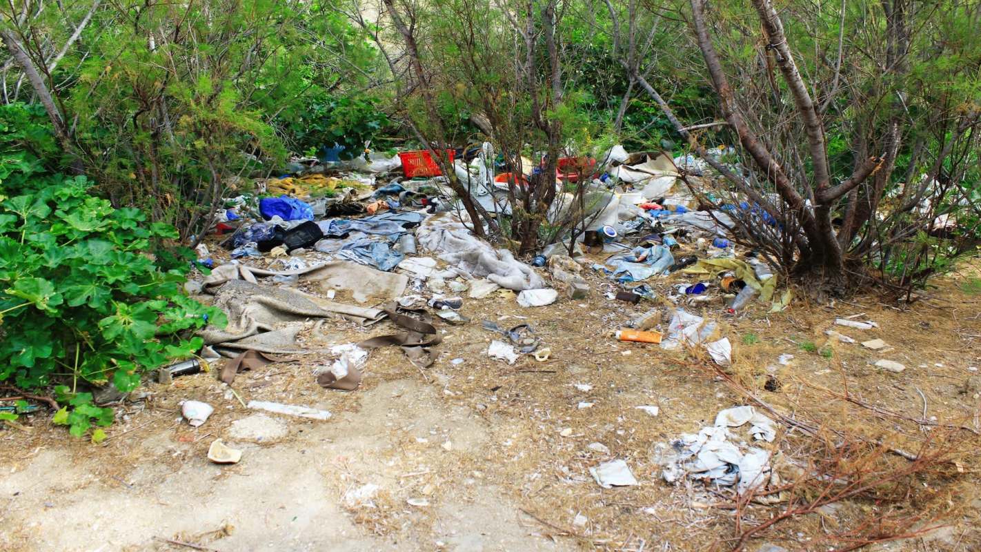 A pile of trash and debris amid greenery.