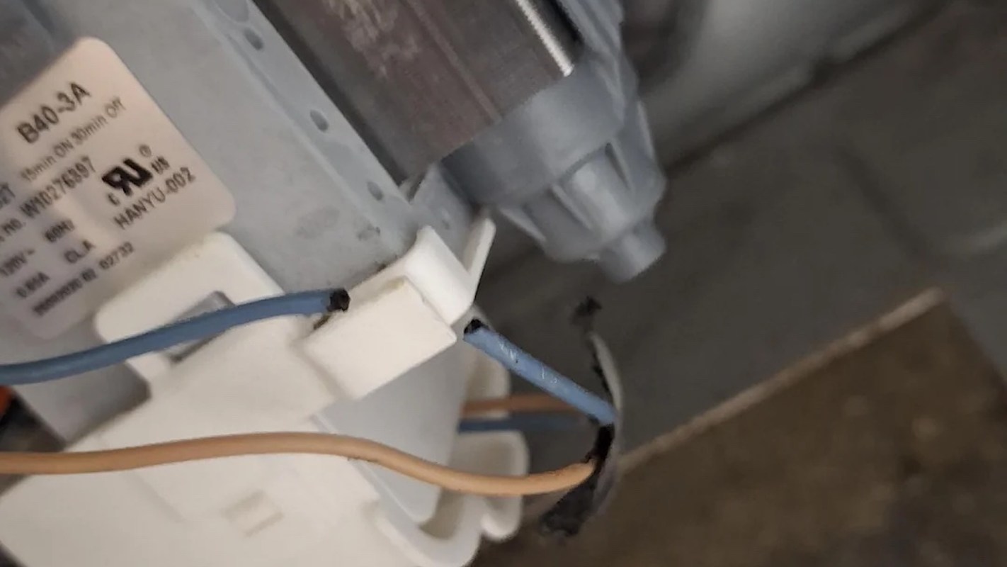 A close-up of electrical wires connected to a component with a label and part number.