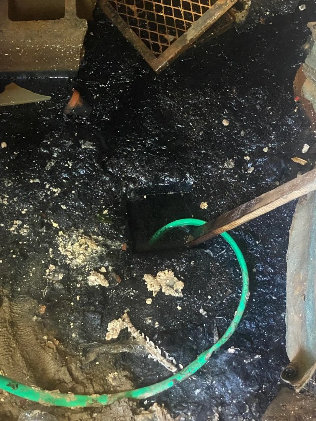 A large amount of black sludge around a drain.