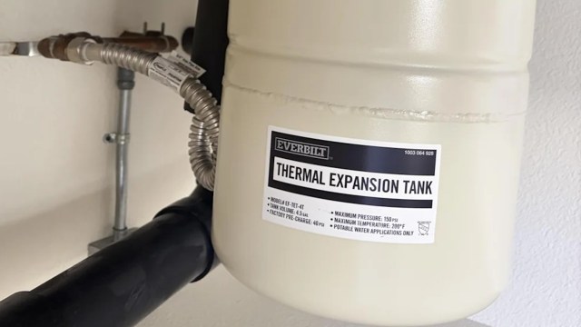 A thermal expansion tank mounted on a wall with a label detailing its specifications.