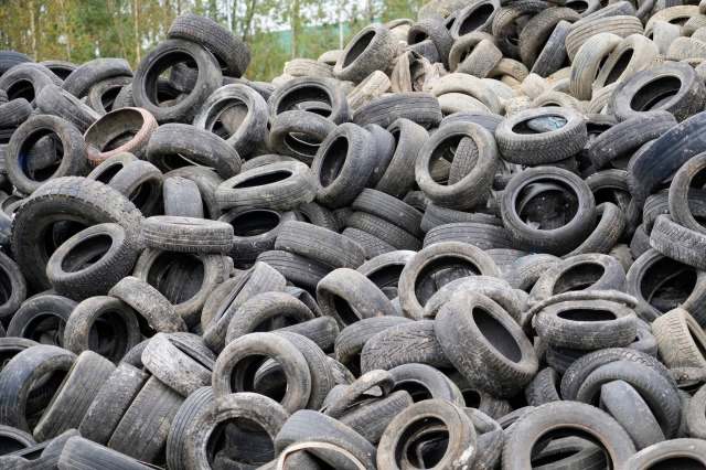 A large pile of worn and discarded tires in a recycling area.