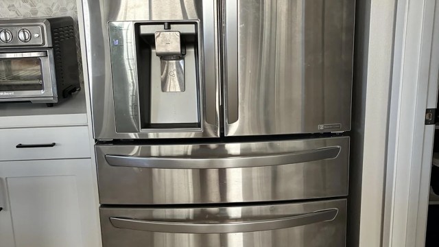 A stainless steel refrigerator with a water dispenser next to a countertop oven.