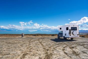 A truck with an attached camper sits and looks out across a vast landscape