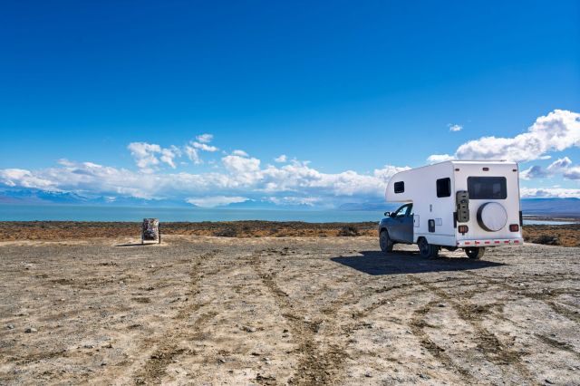 A truck with an attached camper sits and looks out across a vast landscape