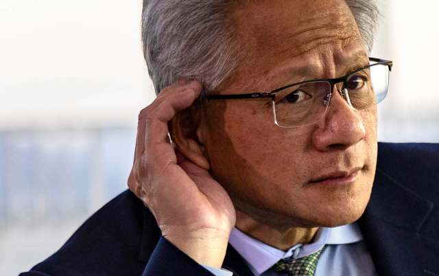 Jensen Huang, CEO of Nvidia, adjusts his glasses and touches his ear while listening attentively.