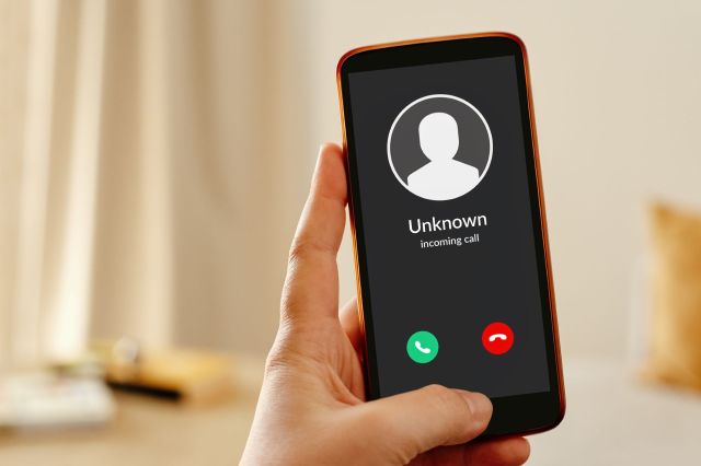 A hand holding a cellphone with an unknown incoming call.