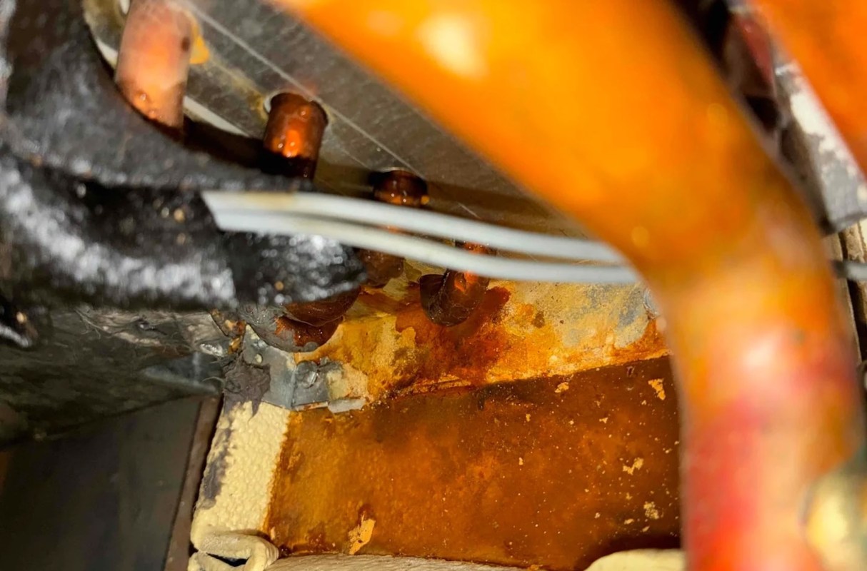 Pipes and wires in a mechanical space with visible rust and discoloration on the surfaces.