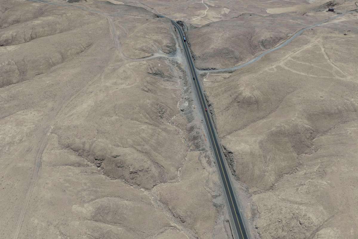 Aerial view of a dry, mountainous landscape with a winding road.