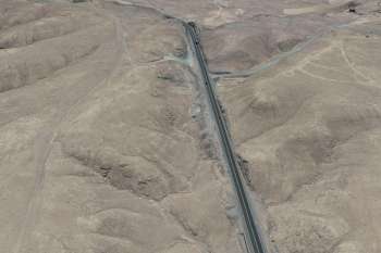 Aerial view of a dry, mountainous landscape with a winding road.