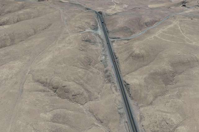 Aerial view of a dry, mountainous landscape with a winding road.