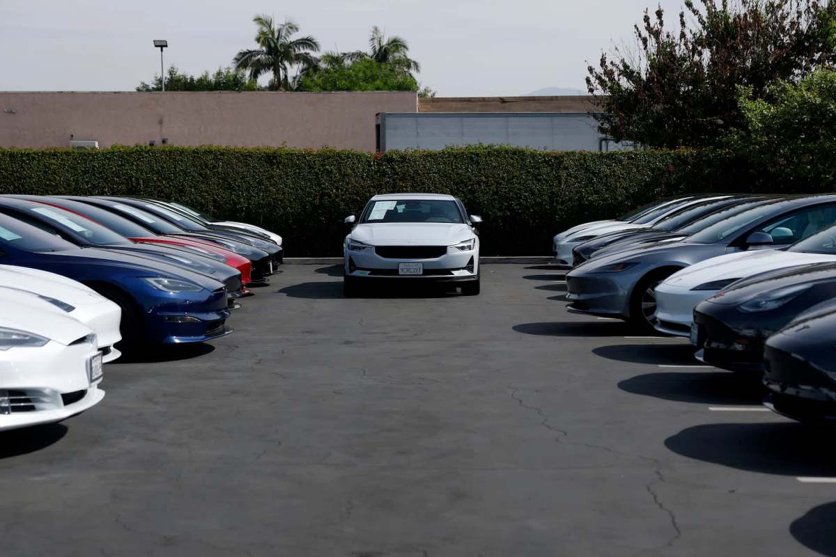 A row of parked cars in a parking lot with a white car positioned in the center.