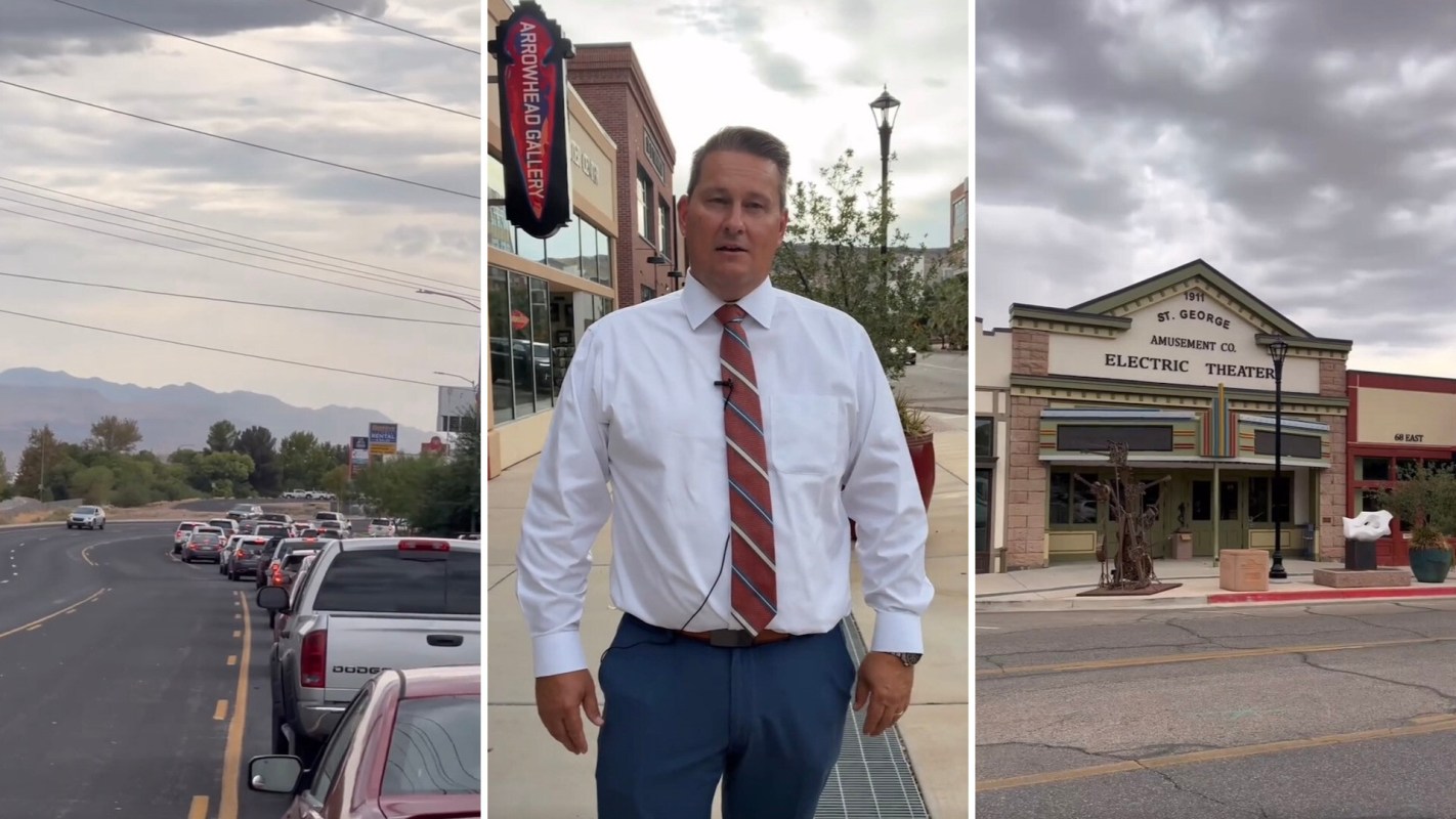 A man stands outside a gallery near a busy street with cars and a historic theater in the background.