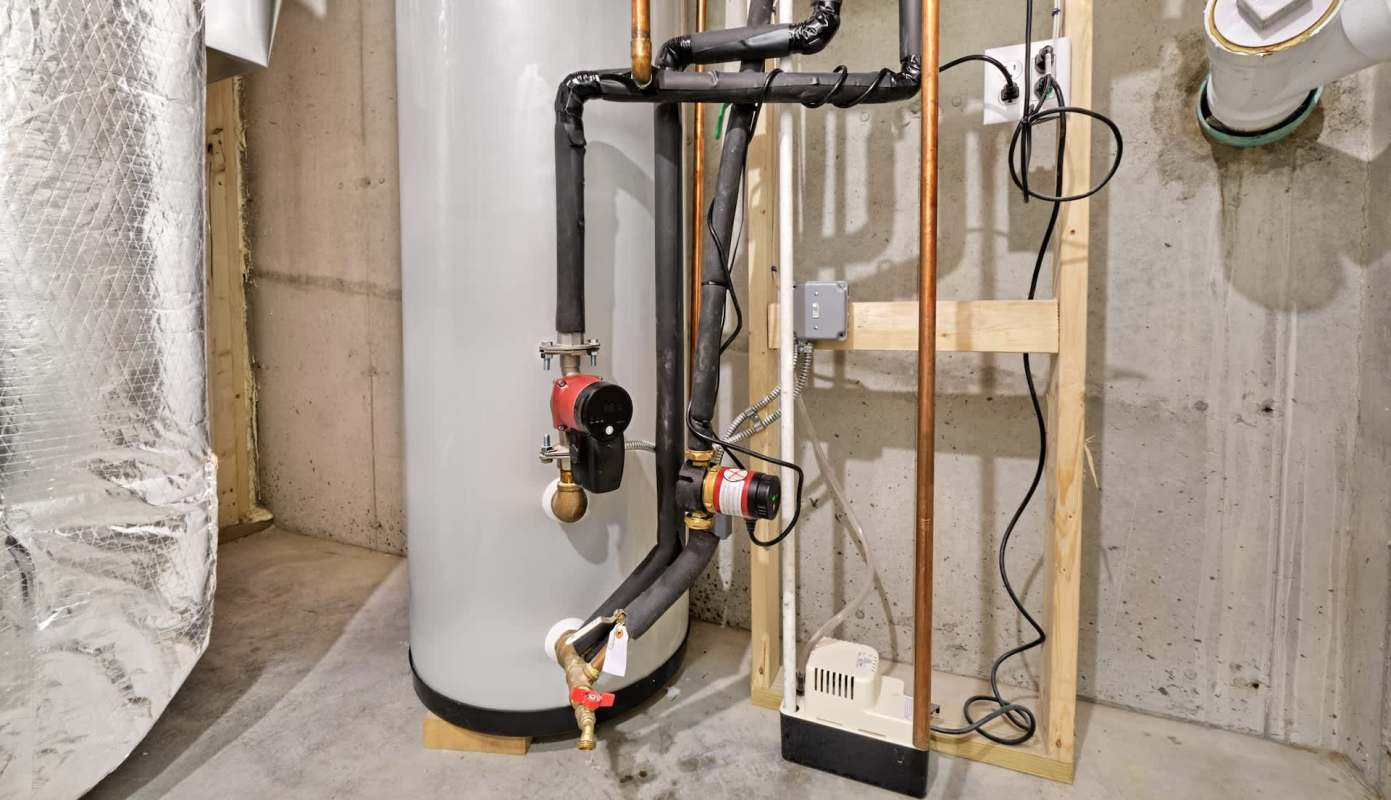 A water heater with connected pipes and a pump in a basement environment.