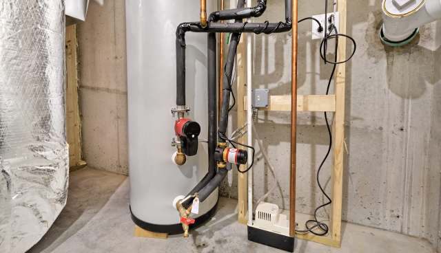 A water heater with connected pipes and a pump in a basement environment.