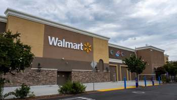 A Walmart store surrounded by trees and parking spaces.
