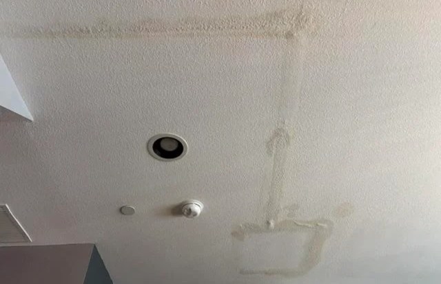 A ceiling with water stains and light fixtures.