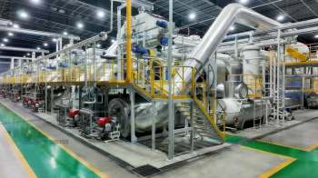 A large industrial facility with machinery, pipes, and staircases for processing.