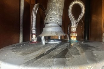 A water heater with rusted pipes and water pooling on the surface.