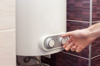 A person adjusts an electric boiler.