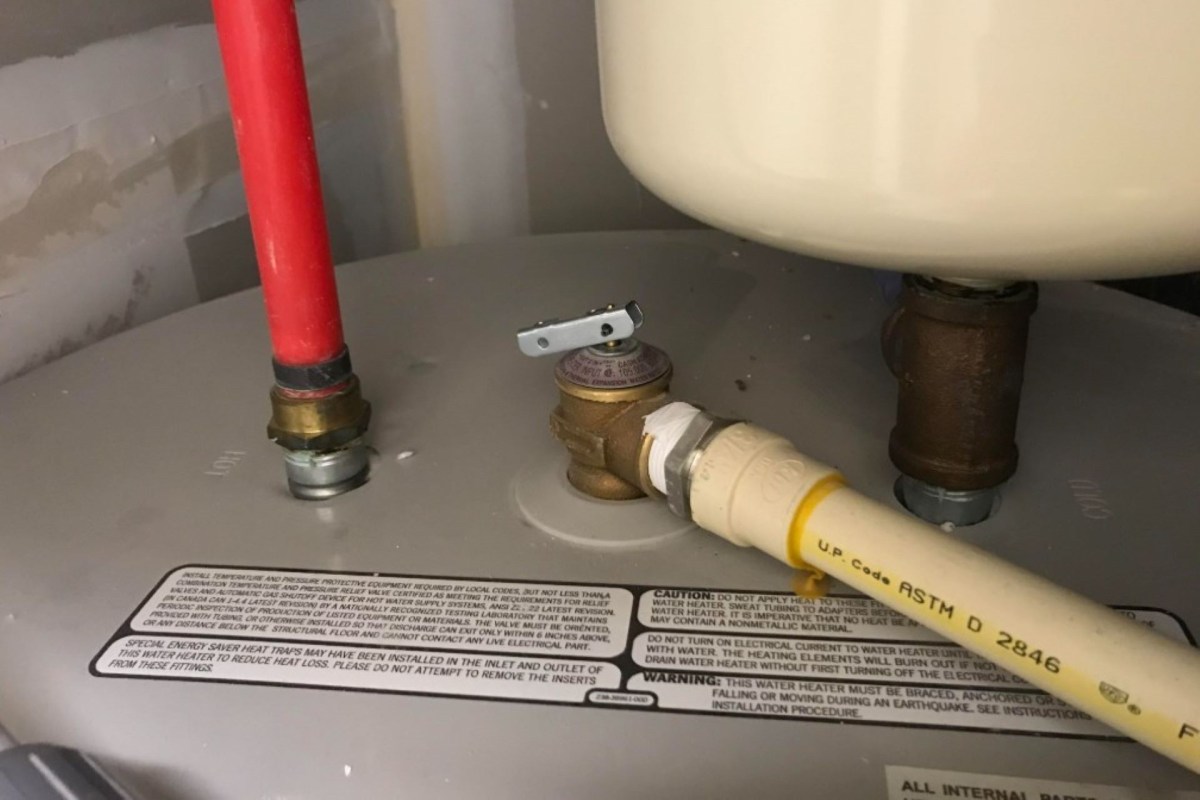 A water heater with pipes and a valve, along with safety and installation instructions on the side.