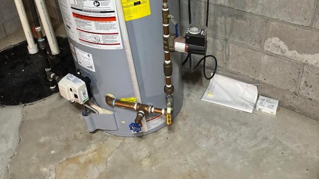 A water heater with connected pipes and valves in a basement setting.