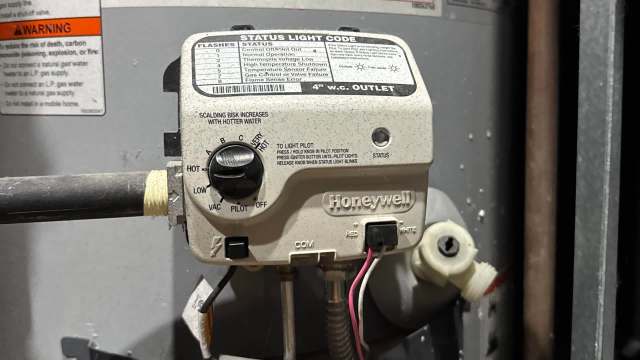 A Honeywell gas control valve with various settings and status indicators, mounted on a water heater.