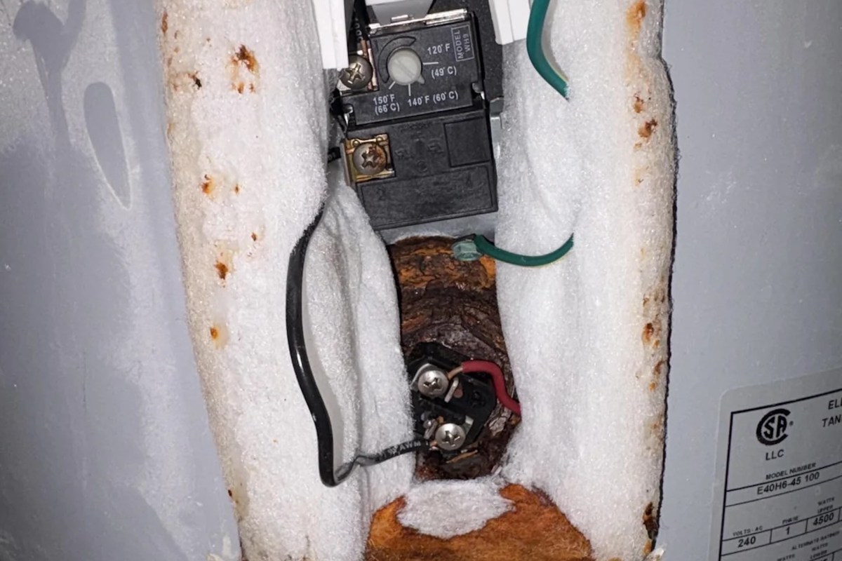 An exposed electrical circuit with wires and a thermostat inside insulation material.
