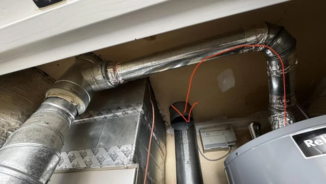 Ductwork and pipes running along the ceiling, with an arrow pointing to an opening in a black pipe.