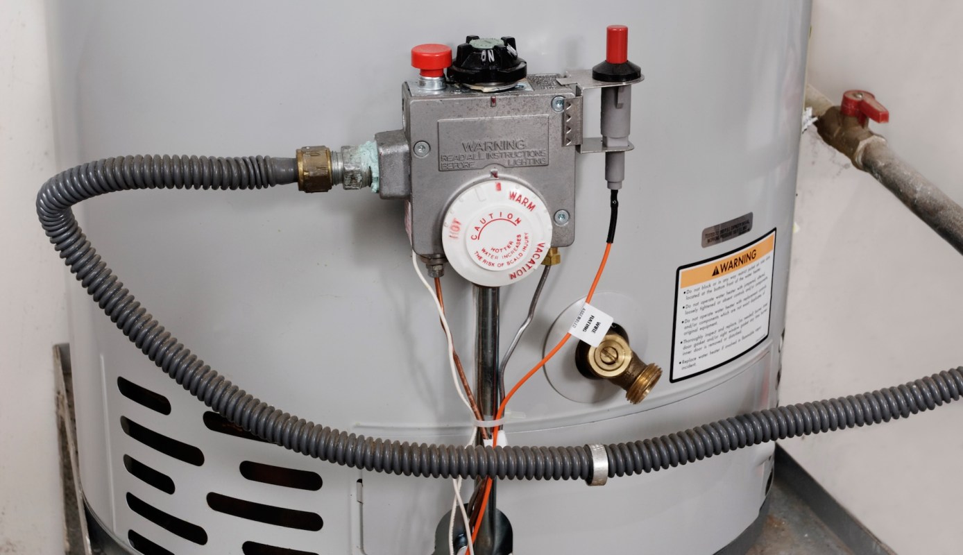 A gas water heater with a pressure valve, temperature control dial, and warning labels.