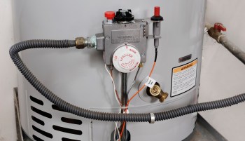 A gas water heater with a pressure valve, temperature control dial, and warning labels.