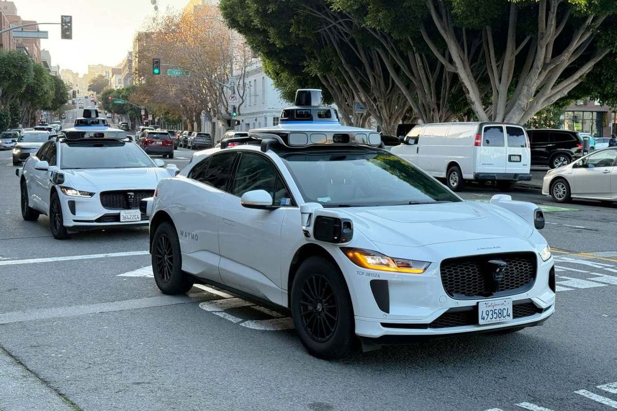 Two Waymo cars driving down a street.