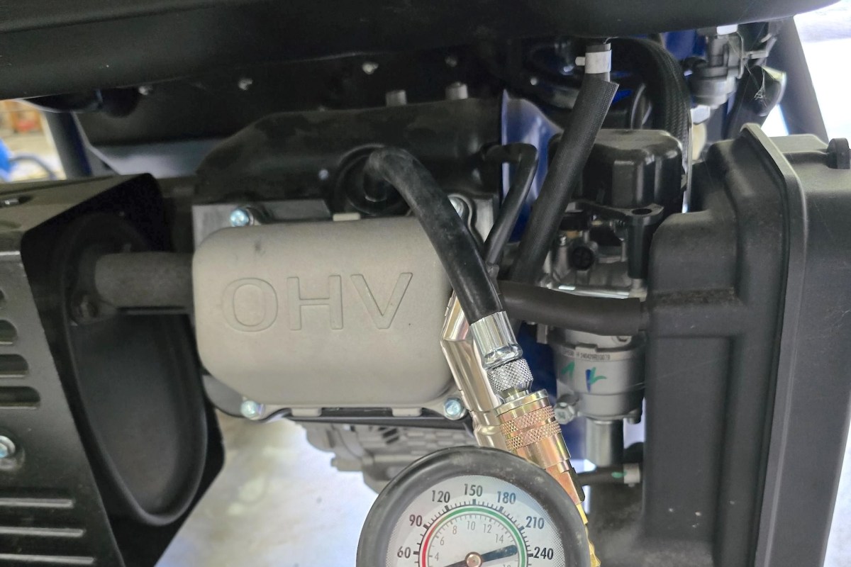 An engine assembly with hoses and a pressure gauge displaying measurement readings.