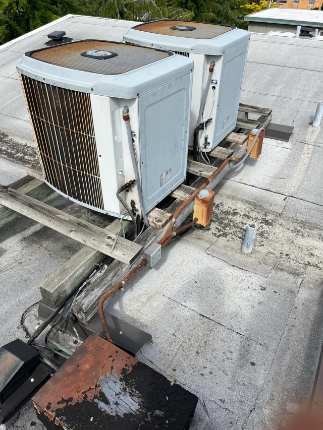 A rooftop heat pump system with visible rust.