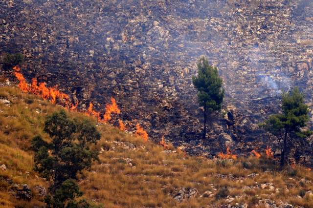A fire on the side of a mountain with burned grass