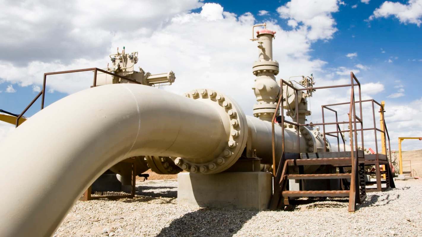 A large pipeline structure with valves and metal stairs in an outdoor setting.