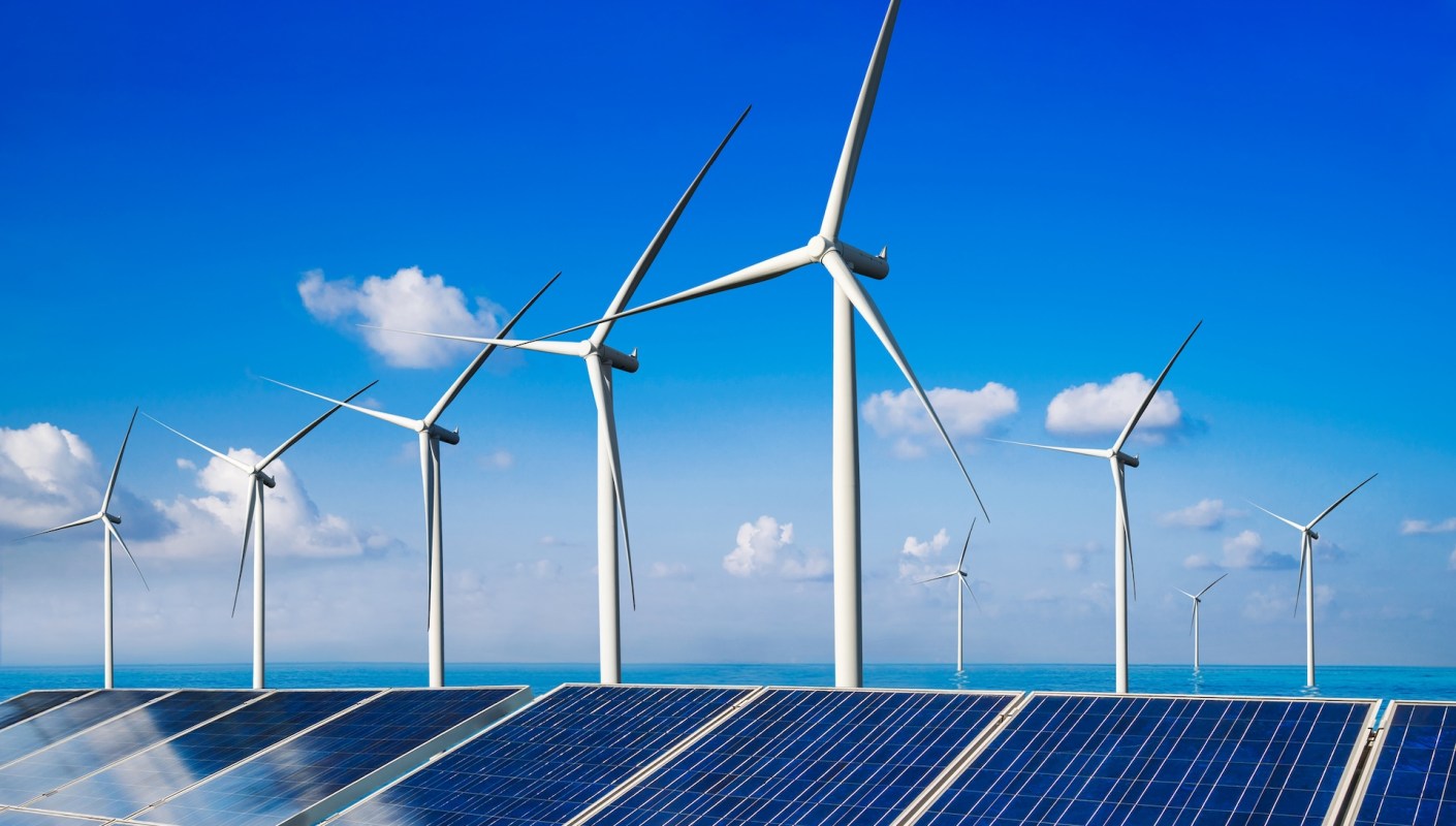 Wind turbines and solar panels are prominently displayed against a blue sky and ocean background.