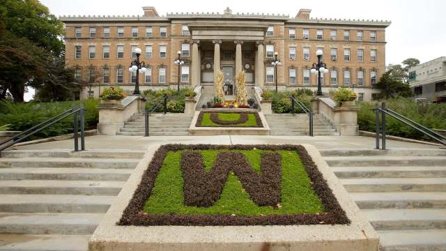A building with architectural columns and landscaped steps featuring greenery and decorative plant arrangements.