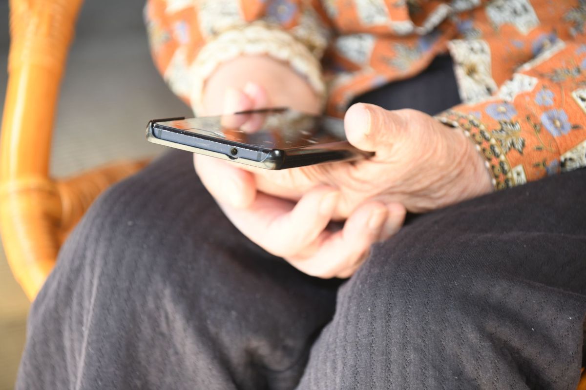 An elderly woman holding a smartphone.