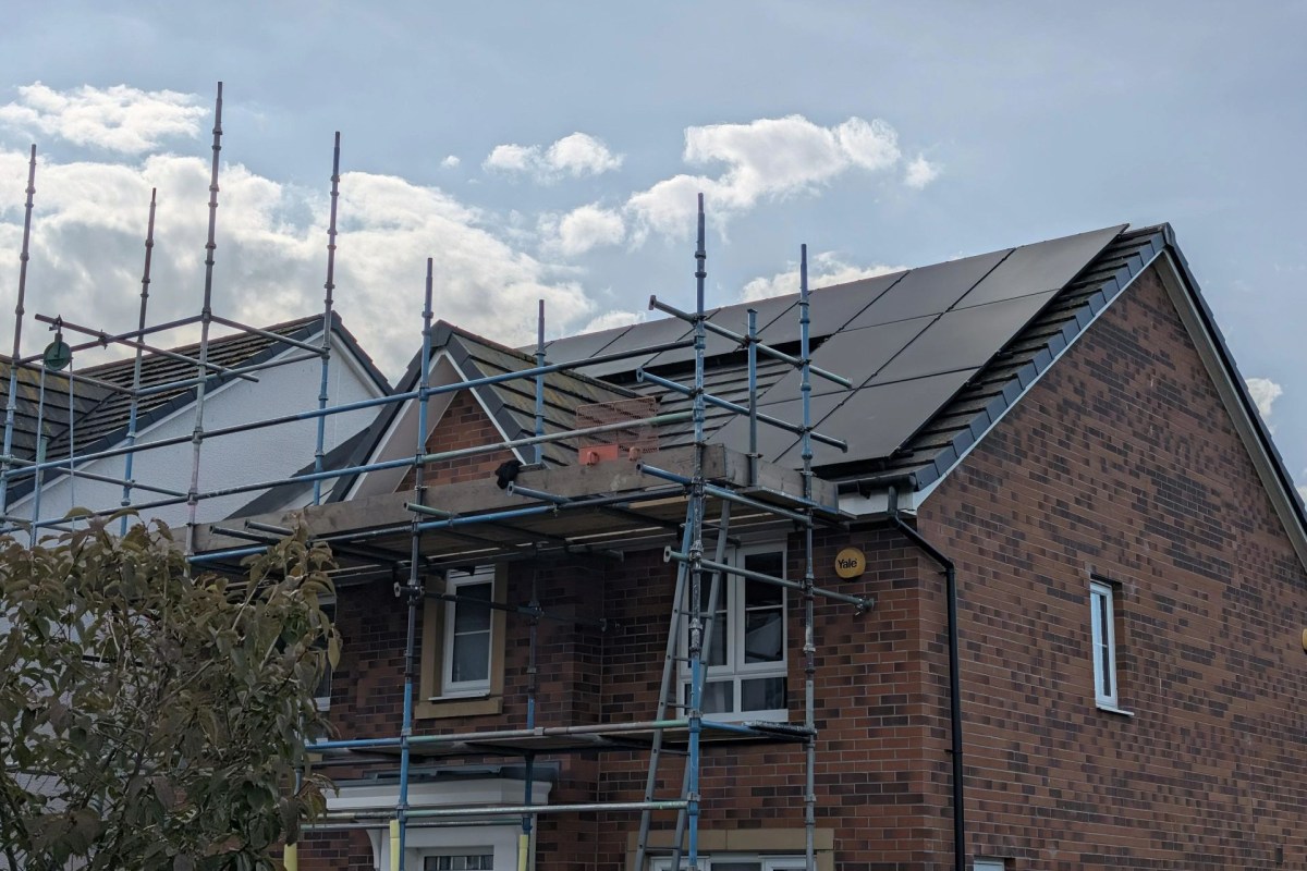 A home with scaffolding in front with solar panels on the roof