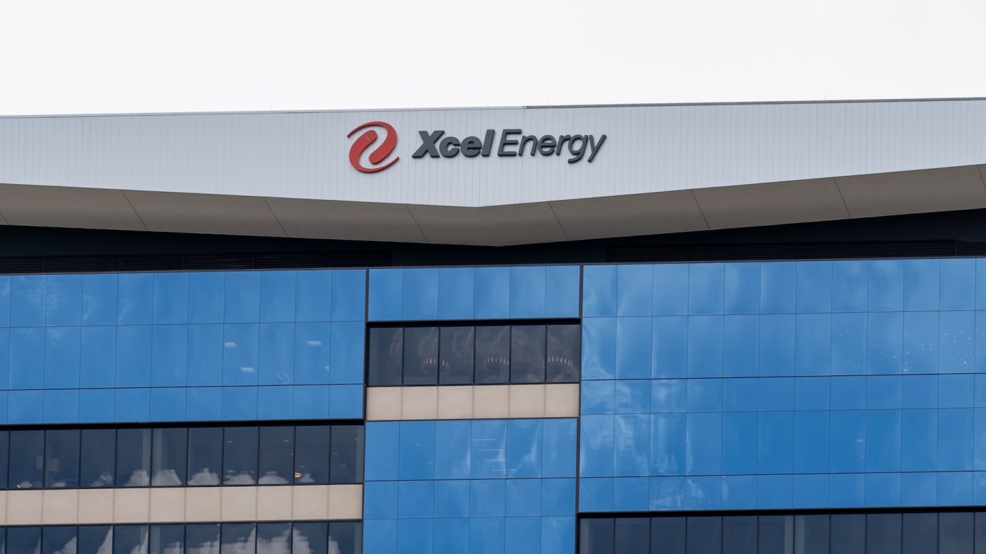 A modern building with blue glass panels and the Xcel Energy logo on the roof.