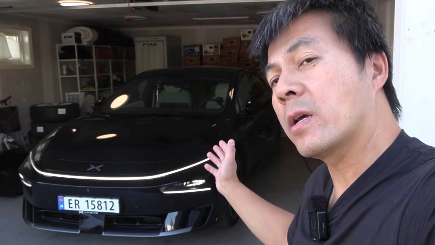 A person gestures toward a black car parked in a garage.