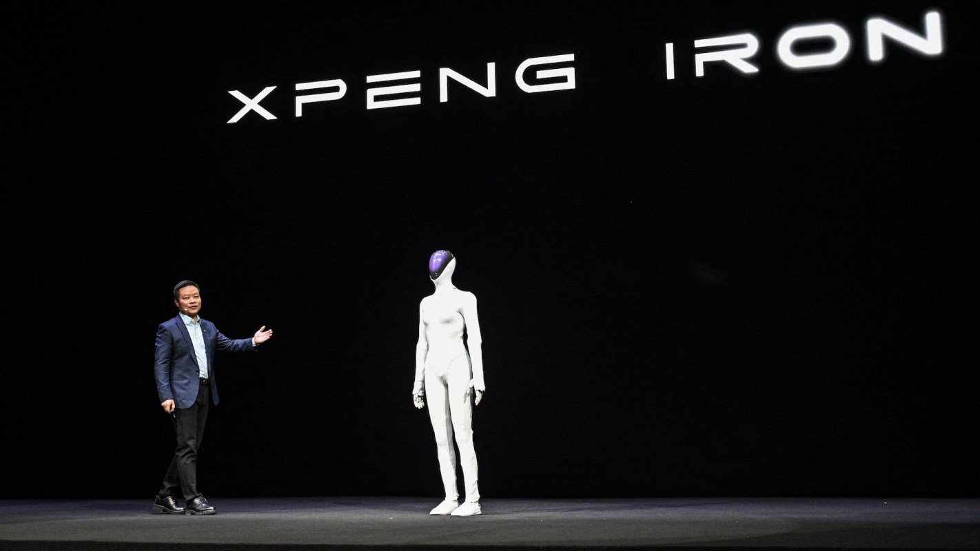 A presenter stands next to a humanoid robot on a stage with the text "XPENG IRON" in the background.