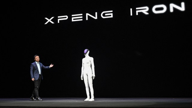 A presenter stands next to a humanoid robot on a stage with the text "XPENG IRON" in the background.