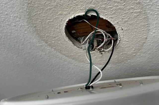 A ceiling hole displaying electrical wires and a surface mount light fixture.
