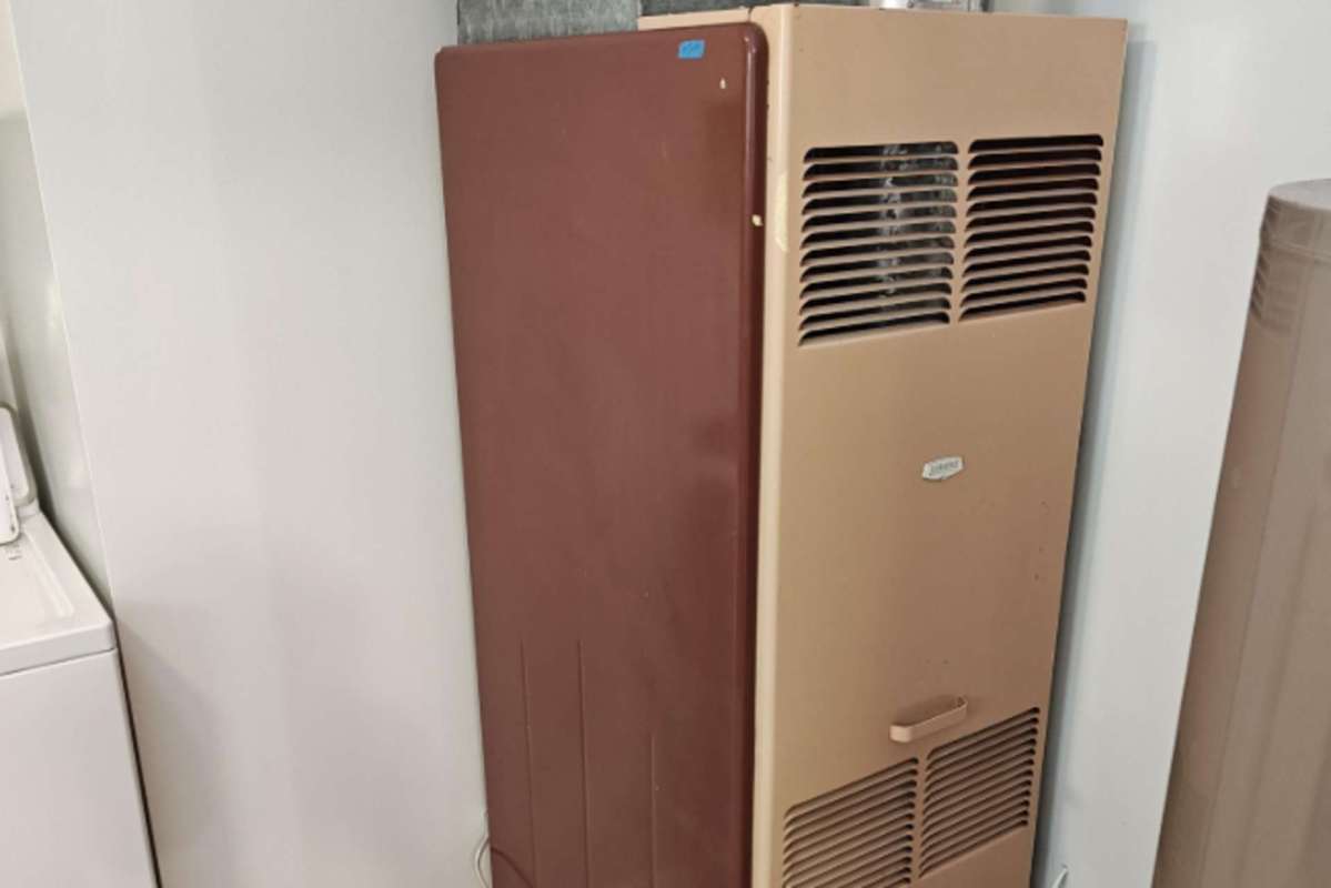A beige and brown vintage furnace positioned against a wall.