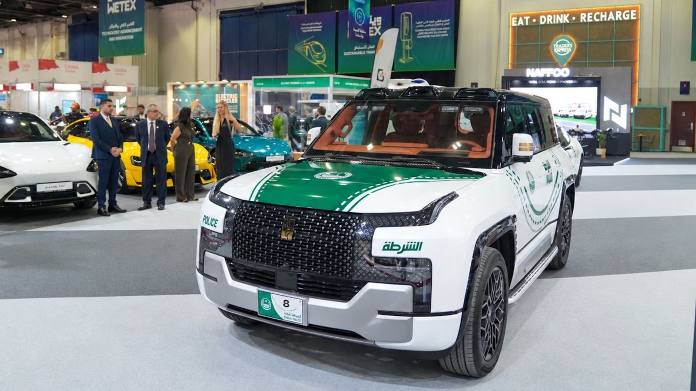 A police SUV displayed at an exhibition, surrounded by other cars and attendees.
