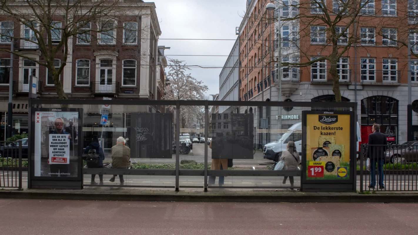 A bus stop with advertisements and people waiting in Amsterdam.