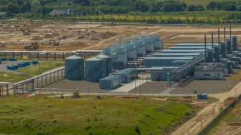 An industrial site with storage tanks, pipelines, and construction areas in the background.