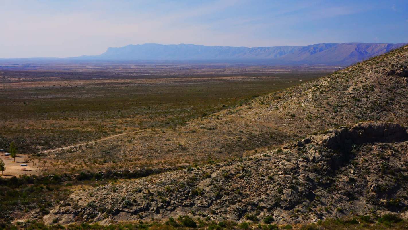 A desert landscape in New Mexico with distant mountains and sparse vegetation.