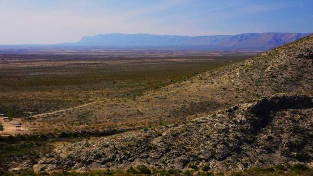 A desert landscape in New Mexico with distant mountains and sparse vegetation.